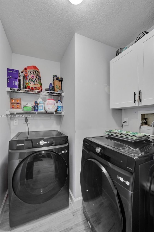 clothes washing area with cabinet space, light wood-style flooring, baseboards, and separate washer and dryer