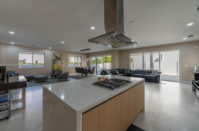 kitchen featuring stainless steel gas cooktop, open floor plan, visible vents, island range hood, and a kitchen island