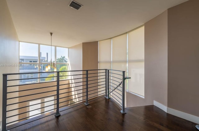hall featuring baseboards, wood finished floors, an upstairs landing, and visible vents