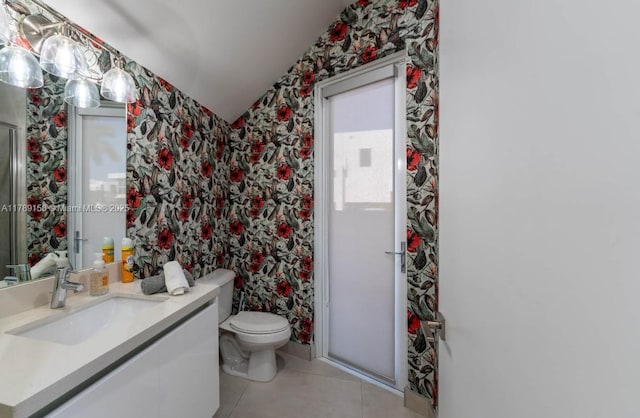 bathroom featuring wallpapered walls, lofted ceiling, tile patterned flooring, toilet, and vanity