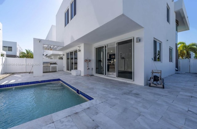rear view of property with exterior kitchen, a fenced in pool, a fenced backyard, a patio, and stucco siding