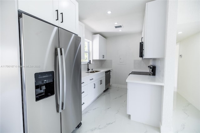 1625 NW 9th Ct, Homestead, FL 33030 - kitchen featuring appliances with stainless steel finishes, a sink, light marble finish flooring, white cabinetry, and decorative backsplash