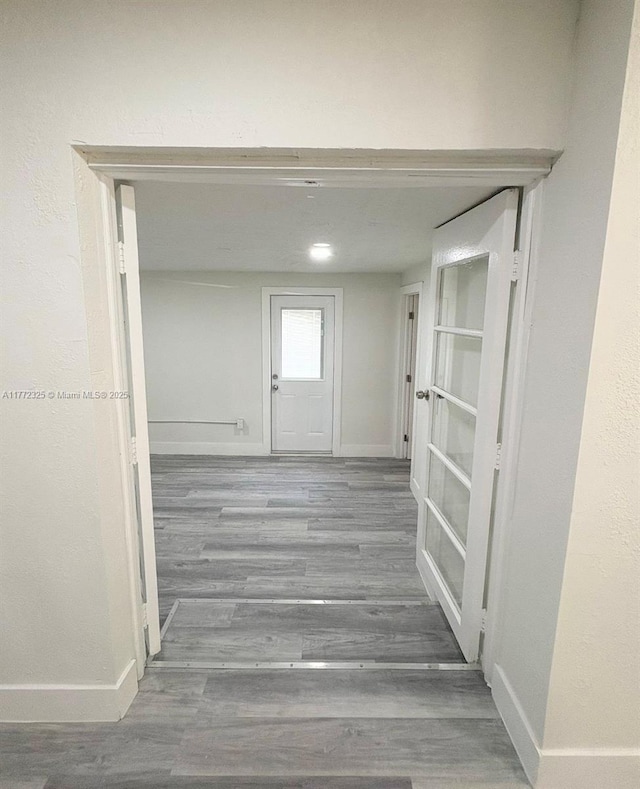 corridor featuring baseboards and wood finished floors