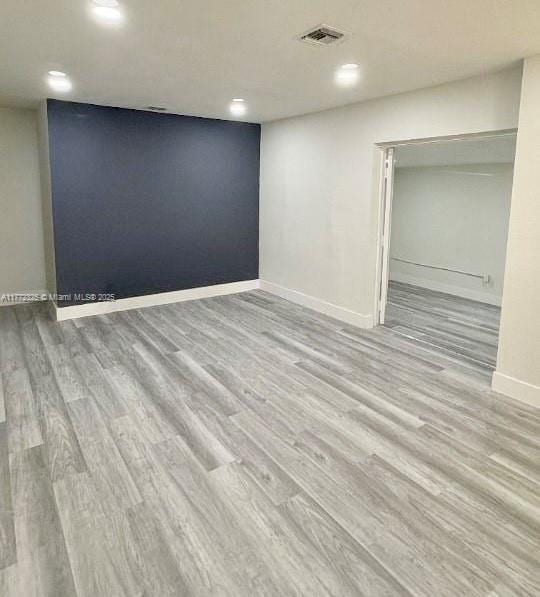 spare room featuring recessed lighting, wood finished floors, visible vents, and baseboards