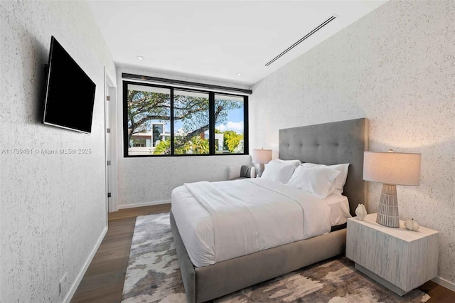 bedroom featuring wood finished floors and a textured wall