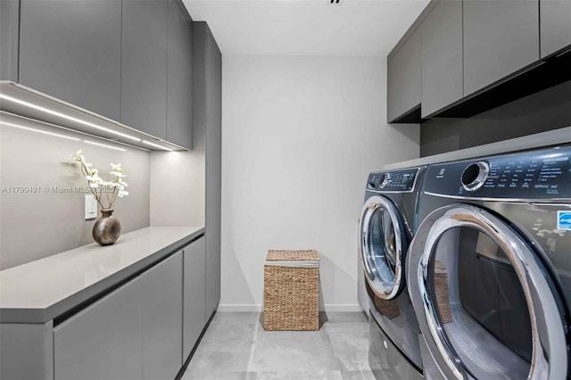 clothes washing area featuring washer and dryer, cabinet space, and baseboards