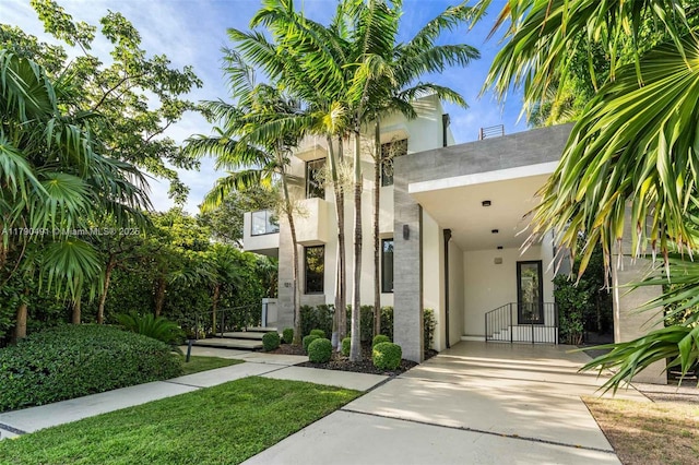 property entrance with an attached carport, driveway, stucco siding, and a gate