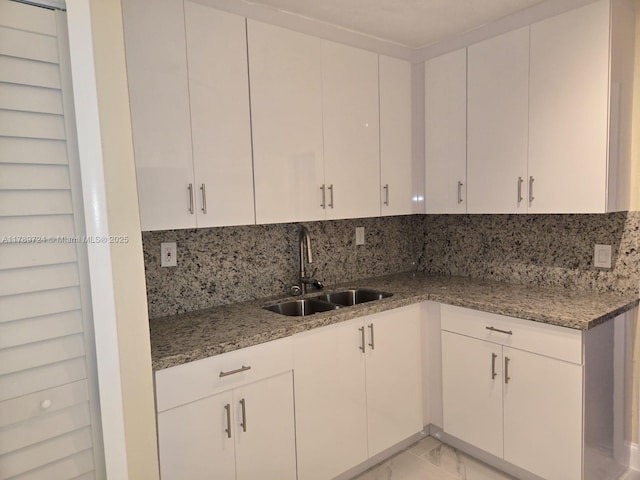 6308 Cleveland St, Hollywood, FL 33024 - kitchen featuring white cabinets, a sink, backsplash, marble finish floor, and light stone counters