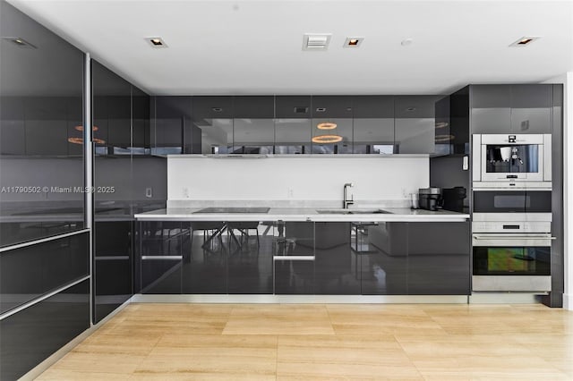 1451 Brickell Ave Unit 1803, Miami, FL 33131 - kitchen with modern cabinets, black electric cooktop, a sink, light countertops, and gray cabinetry