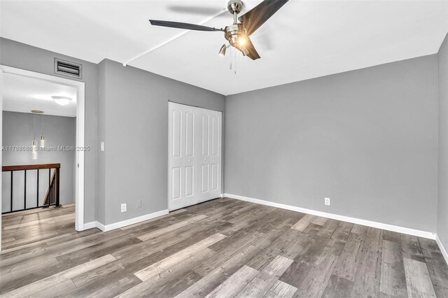 unfurnished bedroom with wood finished floors, baseboards, a closet, and ceiling fan