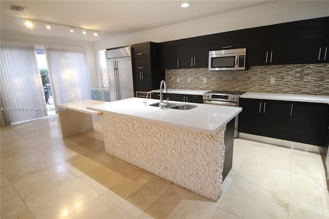 kitchen with dark cabinetry, a sink, appliances with stainless steel finishes, and tasteful backsplash