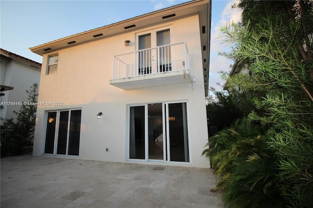 back of house featuring stucco siding, a patio area, and a balcony
