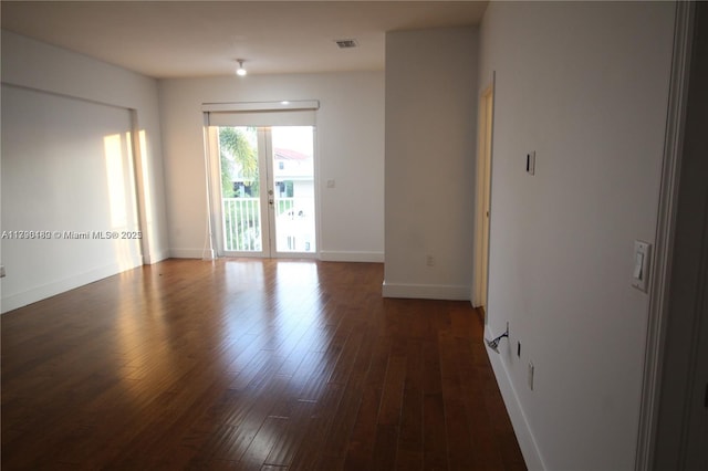 unfurnished room with dark wood-style floors, baseboards, and visible vents