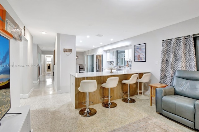 9460 NW 3rd St, Pembroke Pines, FL 33024 - kitchen featuring dark speckled floor, baseboards, high end refrigerator, a peninsula, and a kitchen breakfast bar