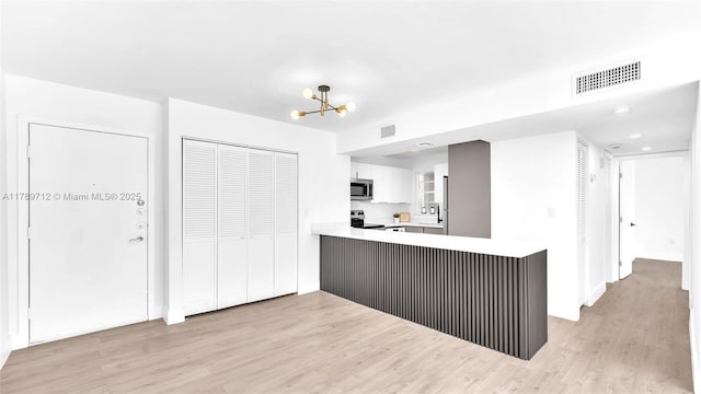 840 NW 87th Ave Unit 204, Miami, FL 33172 - kitchen with stainless steel appliances, light wood-style floors, light countertops, visible vents, and a peninsula