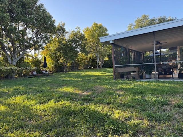 view of yard featuring a ceiling fan and a sunroom