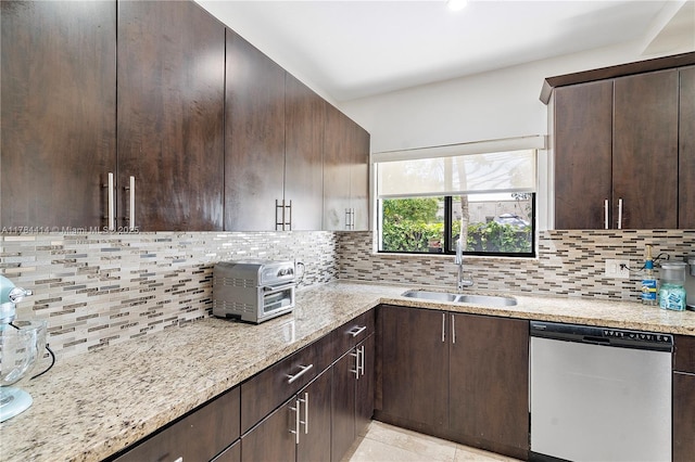 kitchen with dark brown cabinetry, stainless steel dishwasher, decorative backsplash, and a sink