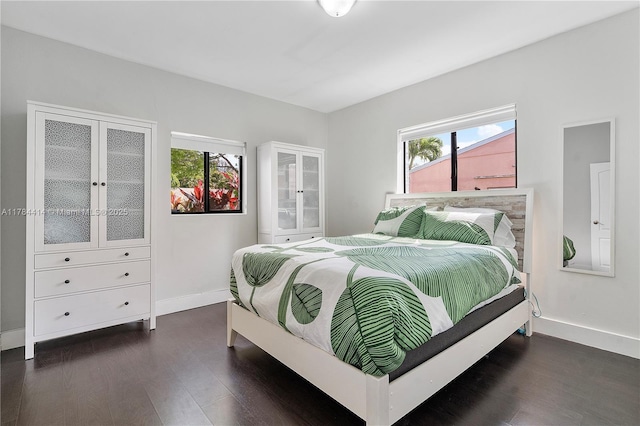 bedroom with dark wood finished floors, baseboards, and multiple windows