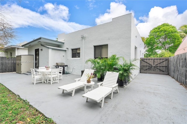 rear view of property with a gate, fence, a patio, and stucco siding