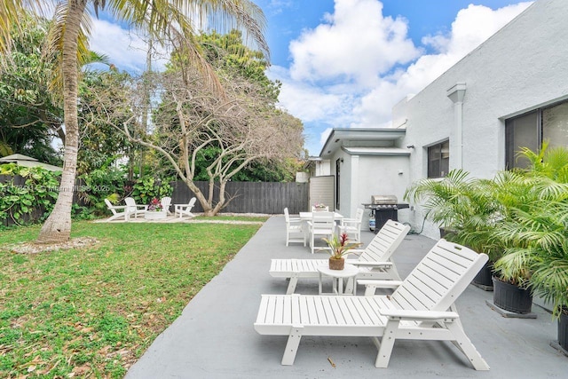view of patio featuring fence, a fire pit, outdoor dining area, and a grill