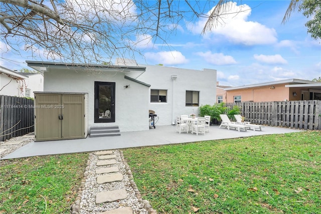 rear view of property with a fenced backyard, a patio area, an outdoor structure, a yard, and stucco siding