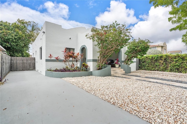 mediterranean / spanish house featuring driveway, stucco siding, and fence