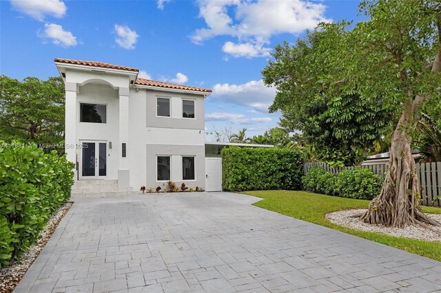 back of property with a tile roof, a lawn, french doors, fence, and stucco siding
