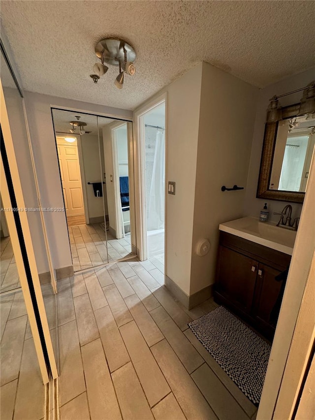 bathroom featuring baseboards, a textured ceiling, and vanity