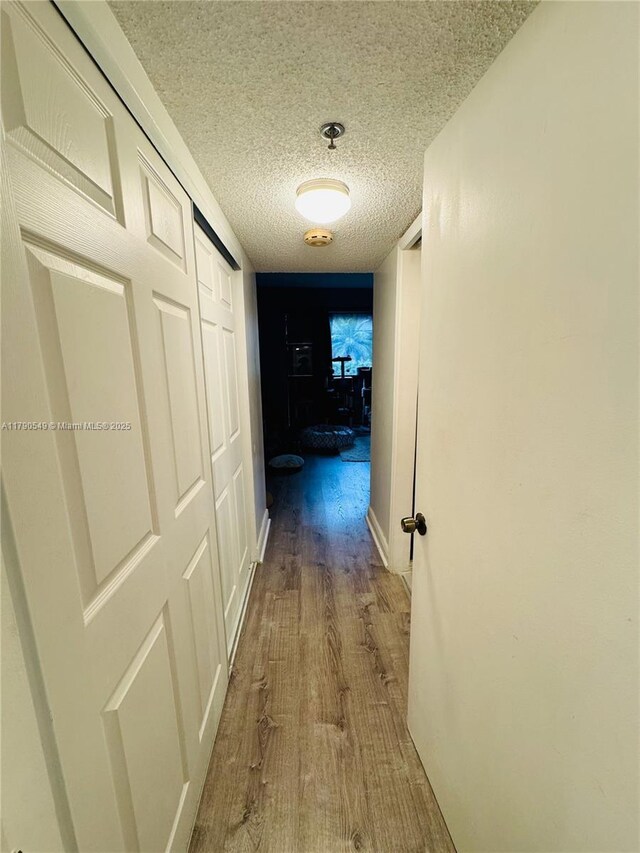 hall with wood finished floors and a textured ceiling
