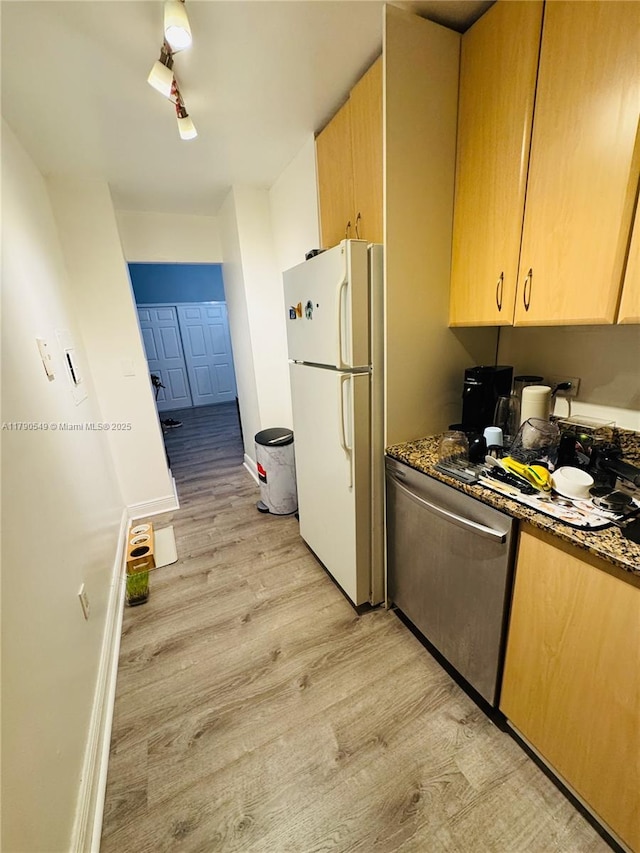 kitchen with light wood finished floors, stainless steel dishwasher, light brown cabinetry, baseboards, and freestanding refrigerator