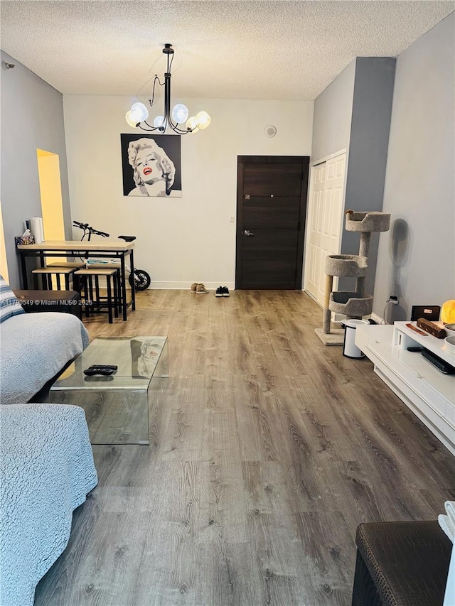 living room with wood finished floors, a textured ceiling, baseboards, and a notable chandelier