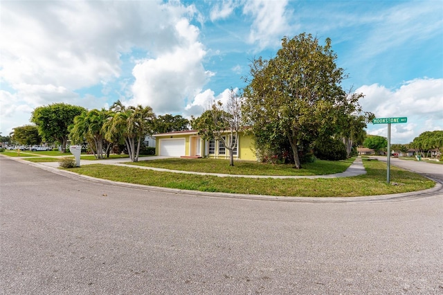 view of front facade with an attached garage, a front yard, driveway, and stucco siding