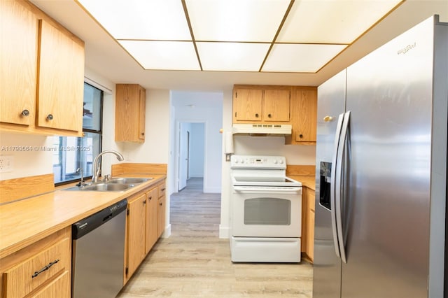 kitchen featuring stainless steel appliances, under cabinet range hood, a sink, light countertops, and light wood finished floors