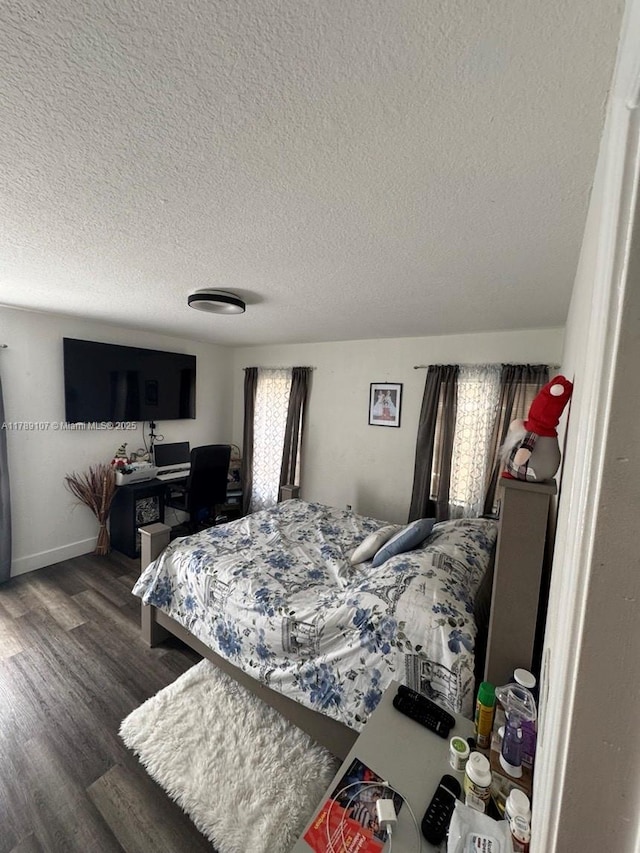 bedroom featuring dark wood finished floors, a textured ceiling, and baseboards