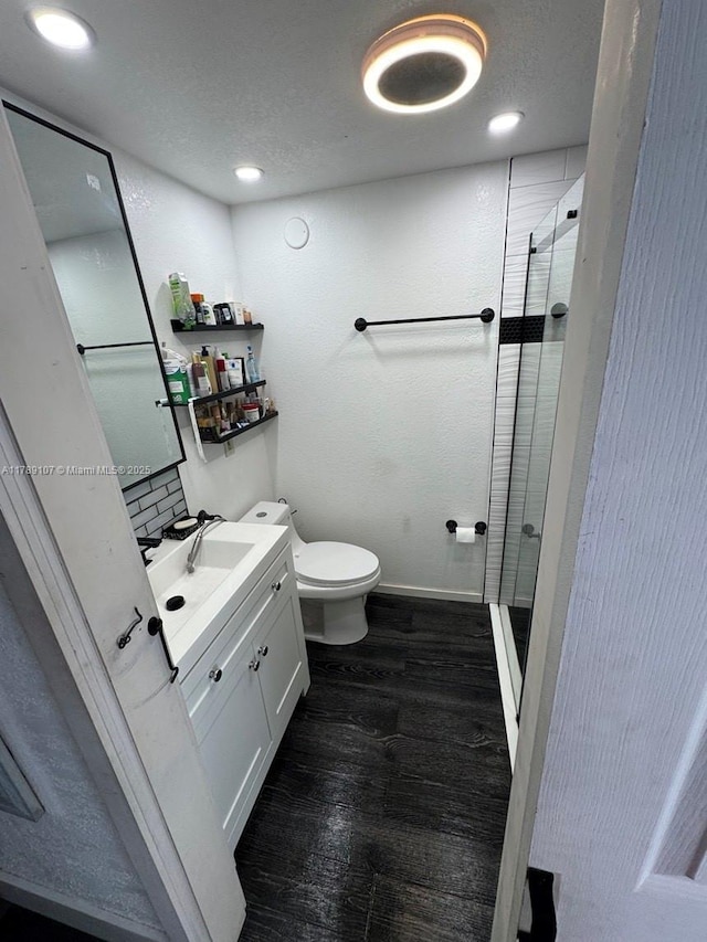 bathroom featuring a shower stall, wood finished floors, toilet, vanity, and baseboards