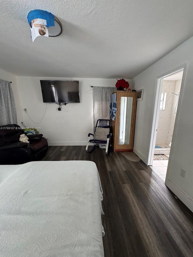 bedroom with ensuite bath, baseboards, a textured ceiling, and dark wood-style flooring