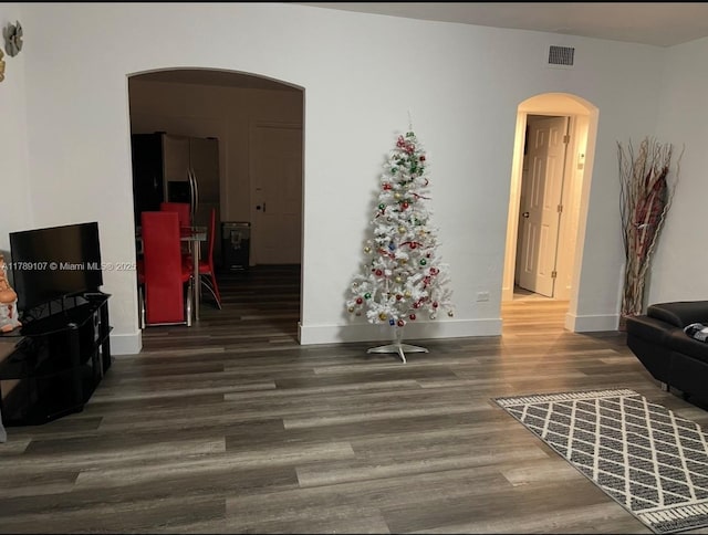 living room with wood finished floors, baseboards, visible vents, and arched walkways