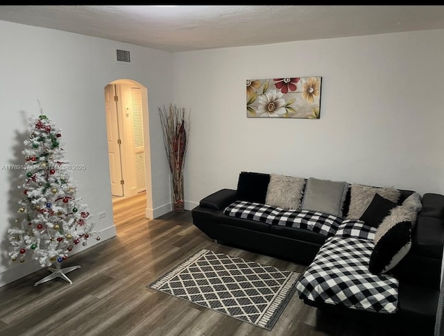 living room with baseboards, visible vents, arched walkways, and wood finished floors
