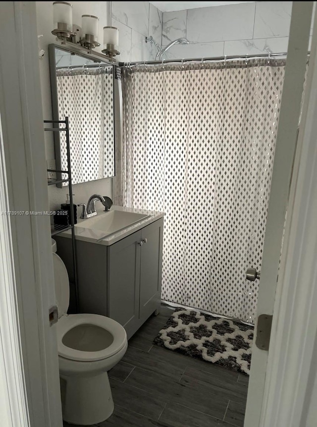 bathroom featuring toilet, vanity, wood finished floors, and curtained shower