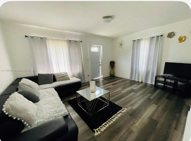 living room with dark wood-style flooring, plenty of natural light, and baseboards