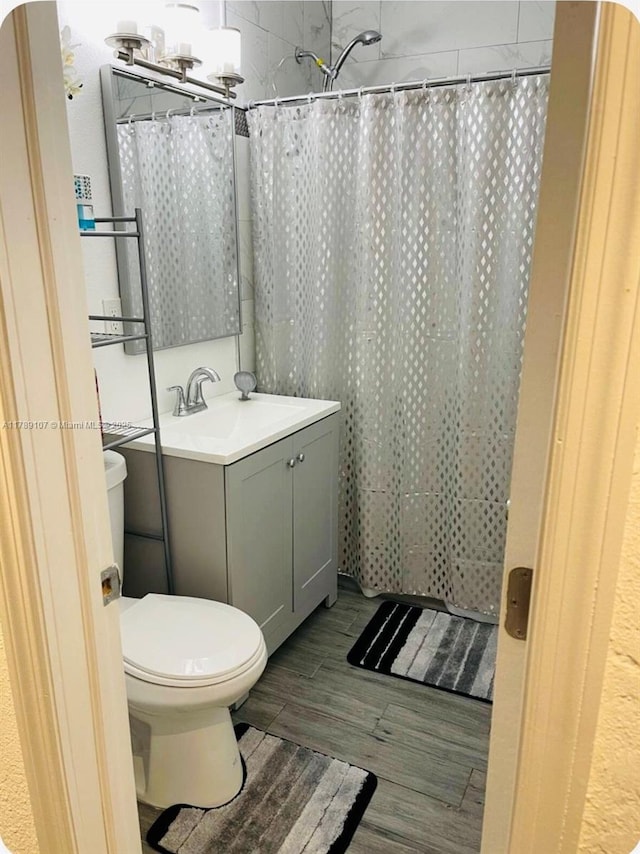 full bath featuring curtained shower, wood finished floors, toilet, and vanity