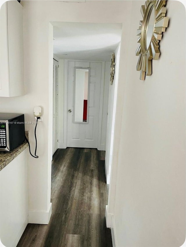 hall featuring baseboards and dark wood finished floors