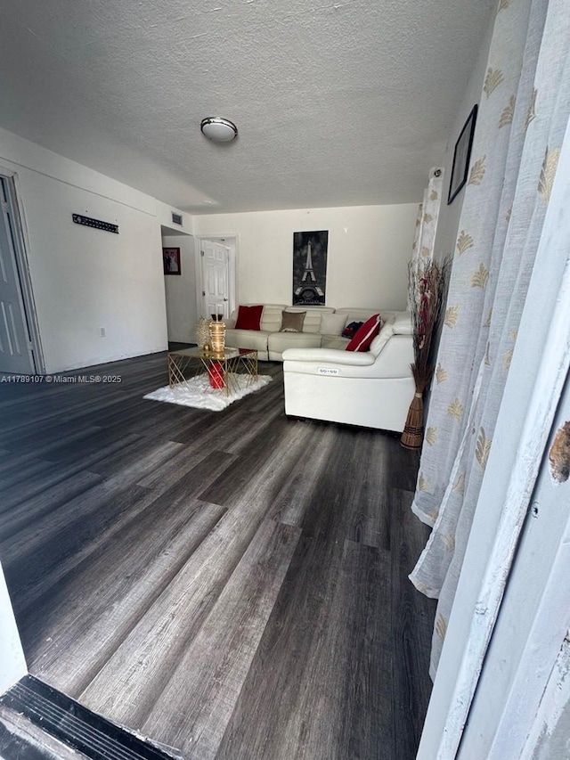 living area featuring a textured ceiling, wood finished floors, and visible vents