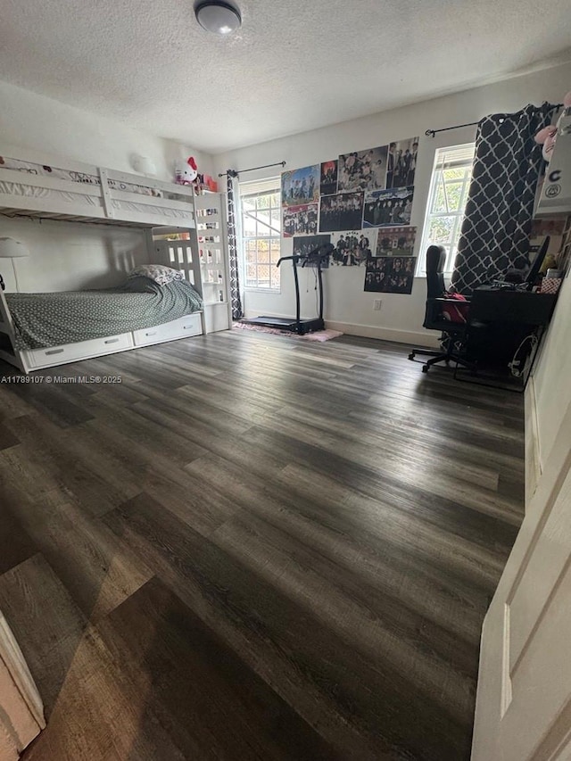 bedroom with baseboards, wood finished floors, a textured ceiling, and multiple windows