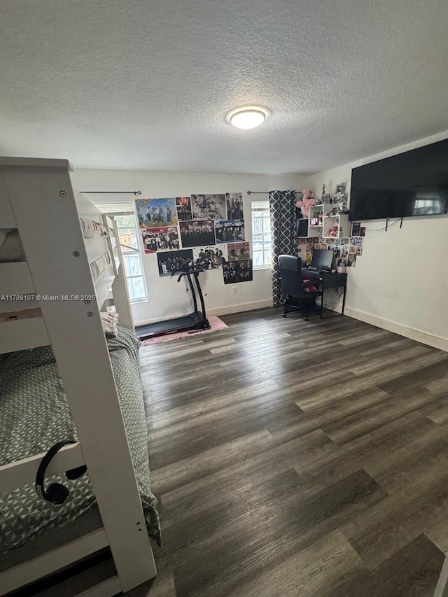 workout area featuring a textured ceiling, wood finished floors, and baseboards