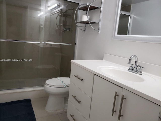 bathroom featuring tile patterned floors, vanity, a shower stall, and toilet