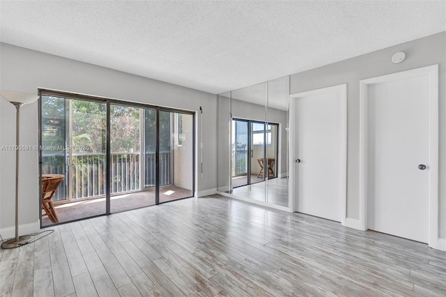 1810 New Palm Way Unit 214, Boynton Beach, FL 33435 - empty room featuring a textured ceiling, light wood-style flooring, and baseboards