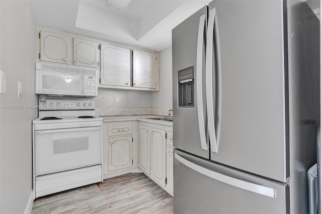 1810 New Palm Way Unit 214, Boynton Beach, FL 33435 - kitchen featuring white appliances, light wood-type flooring, light countertops, a tray ceiling, and a sink