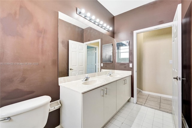 bathroom featuring toilet, double vanity, a sink, and tile patterned floors