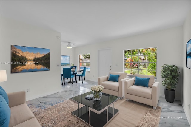living room featuring baseboards, ceiling fan, and marble finish floor